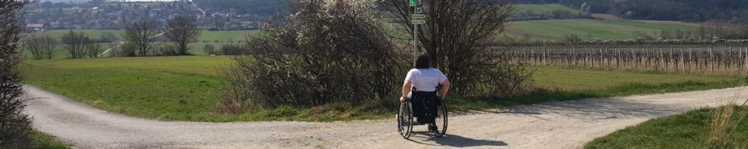 Rollstuhlfahrerin an einer Wegkreuzung