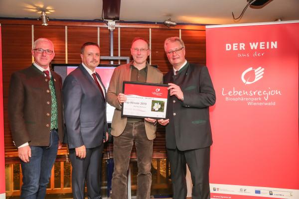 Biosphärenpark Direktor DI Andreas Weiß (l.), Wiener LAbg. Ernst Holzmann (2.v.l.) und NÖ LAbg. Christoph Kainz (r.) gratulieren dem Weingut Barbach zum Top-Winzer 2019.