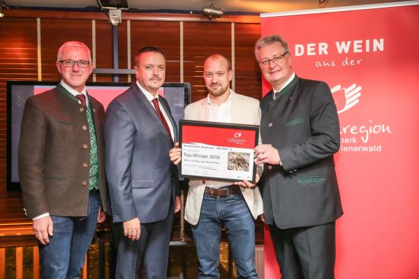 Biosphärenpark Direktor DI Andreas Weiß (l.), Wiener LAbg. Ernst Holzmann (2.v.l.) und NÖ LAbg. Christoph Kainz (r.) gratulieren dem Wein und Heurigen Daniel Plos zum Top-Winzer 2019.