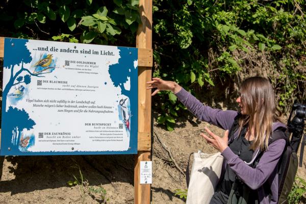 Exkursionsleiterin zeigt auf Infotafel