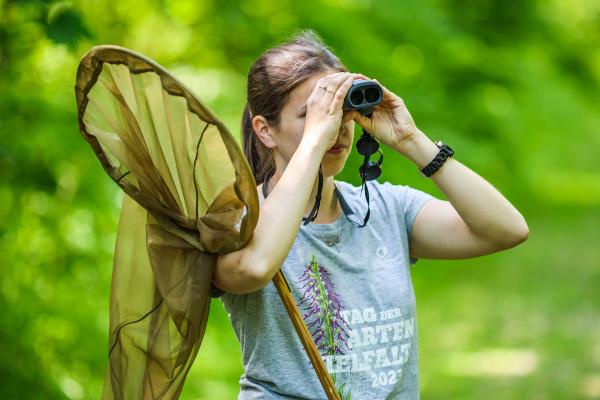 Frau mit Schmetterlingsnetz und Fernglas