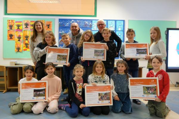 Bürgermeister Michael Krischke und Biosphärenpark-Direktor Andreas Weiß überreichen als Dankeschön die Urkunden stellvertretend an einige Schüler und Schülerinnen der ÖKO-Volksschule Wienerwald mit Direktorin Hermine Noth.