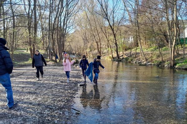 Kinder beim Müllsammeln im Bach