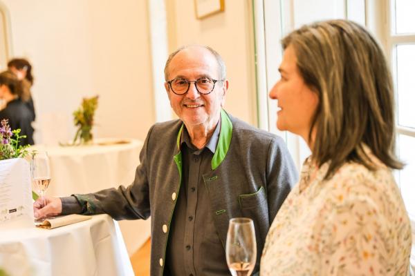 Herr und Frau von der Seite mit Weingläsern bei einem  Stehtisch