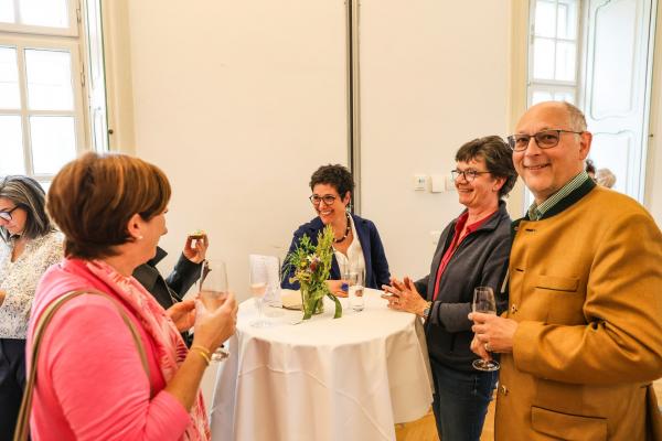 Personengruppe unterhält sich bei Stehtisch mit Blumendeko