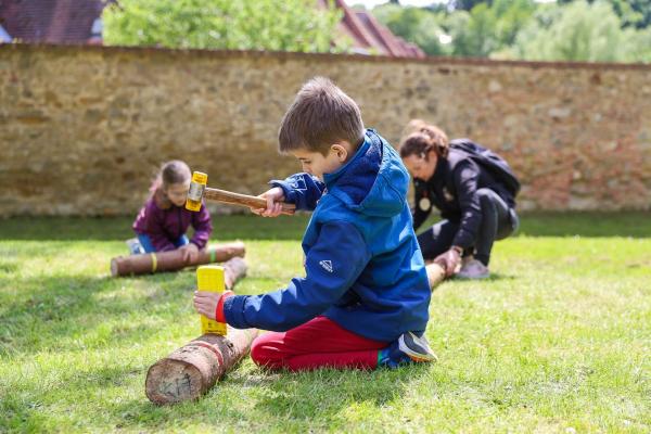 Kinder beim spielerischen Holzhacken.