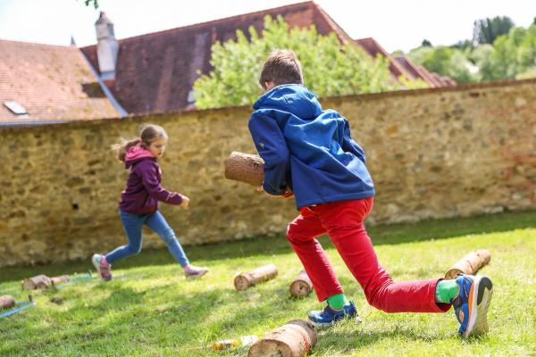 Kinder laufen mit Holzscheiten um die Wette