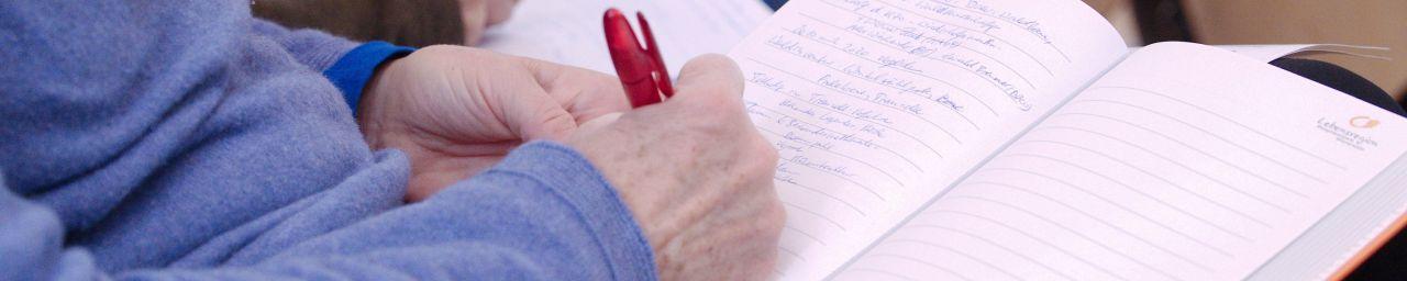 Mann schreibt in ein Notizbuch