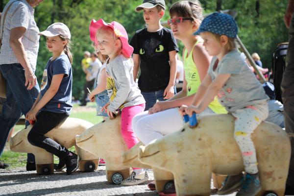 Kinder sitzen auf Wildschweinfiguren aus Holz