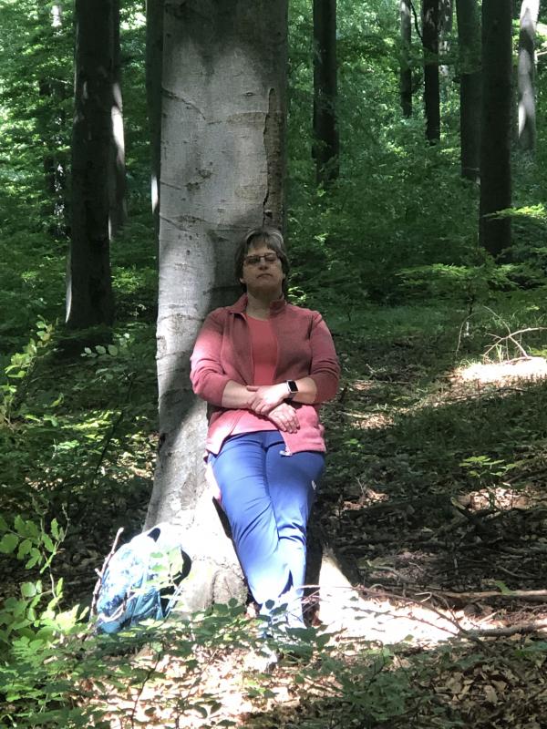 Frau lehnt sich an Baum und entspannt sich