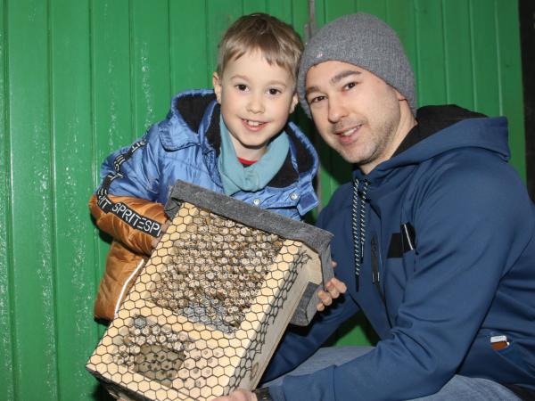 Ein Mann und ein Junge halten eine Bienenkiste.