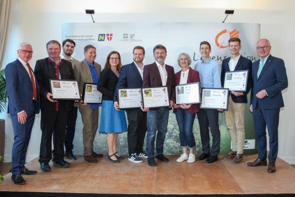 Biosphärenpark-Direktor DI Andreas Weiß (links außen), Wiener LAbg. Mag.a Andrea Mautz (5.v.l.) und NÖ LH-Stv. Dr. Stephan Pernkopf (rechts außen) gratulieren den 6 Top-Weinbaubetrieben 2025 (v.l.n.r.): Weingut Hecher, Weingut Biegler, Weingut Johannes Gebeshuber, Bio-Weingut Frühwirth, Weinbau Zechmeister und Weinbau Karl & Karl jun. Wölflinger.