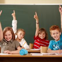 Kinder in einer Schulklasse zeigen auf