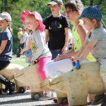 Kinder sitzen auf Wildschweinfiguren aus Holz