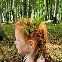 Mädchen mit Blättern im Haar mit Wald im Hintergrund
