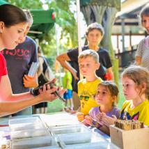 interessierte Erwachsene und Kinder schauen sich am Infostand eine Schlangean