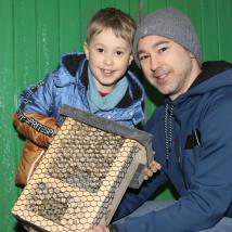 Ein Mann und ein Junge halten eine Bienenkiste.