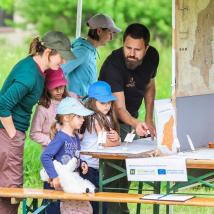 Erwachsene und Kinder spielen bei einer Wissenstation