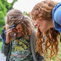 Kind und Erwachsene schauen in eine Becherlupe